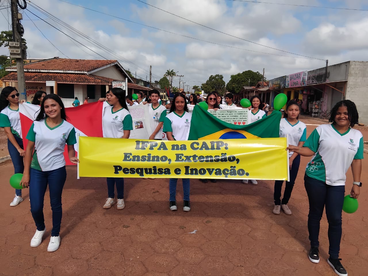 Alunos em desfile segurando cartazes. O cartaz do meio diz: "IFPA na CAIP: Ensino, Extensão, Pesquisa e Inovação". Alunos em desfile segurando cartazes. O cartaz do meio diz: "IFPA na CAIP: Ensino, Extensão, Pesquisa e Inovação".